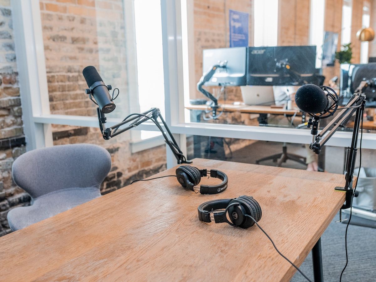 Podcast studio with two microphones, two headsets, and one grey chair.